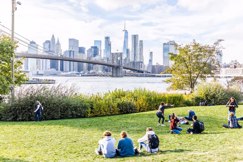 Brooklyn, USA - October 28, 2017: Dumbo outside exterior outdoors in NYC New York City, people in green, urban Main Street Park, cityscape skyline and bridge with east river