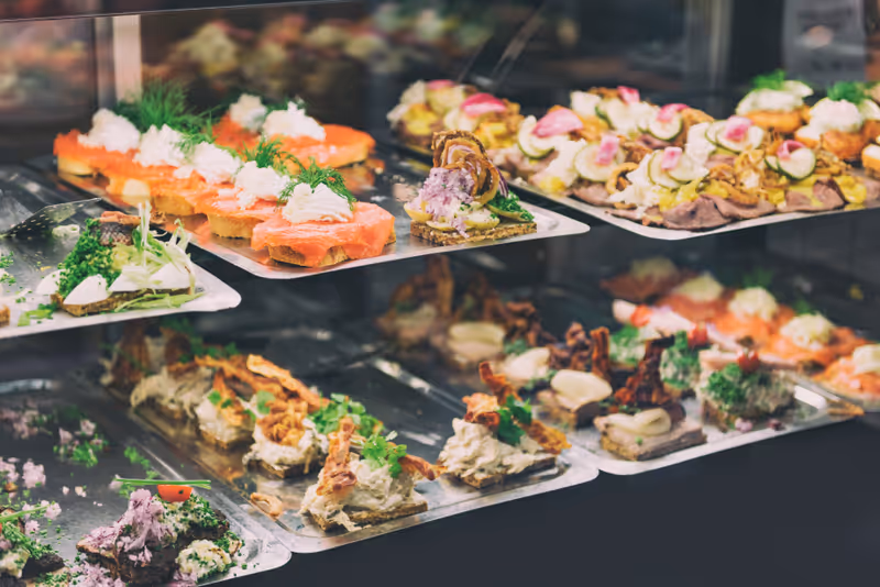 Danish smorrebrod traditional open sandwich at Copenhagen food market store. Many sandwiches on display with seafood and meat, smoked salmon.