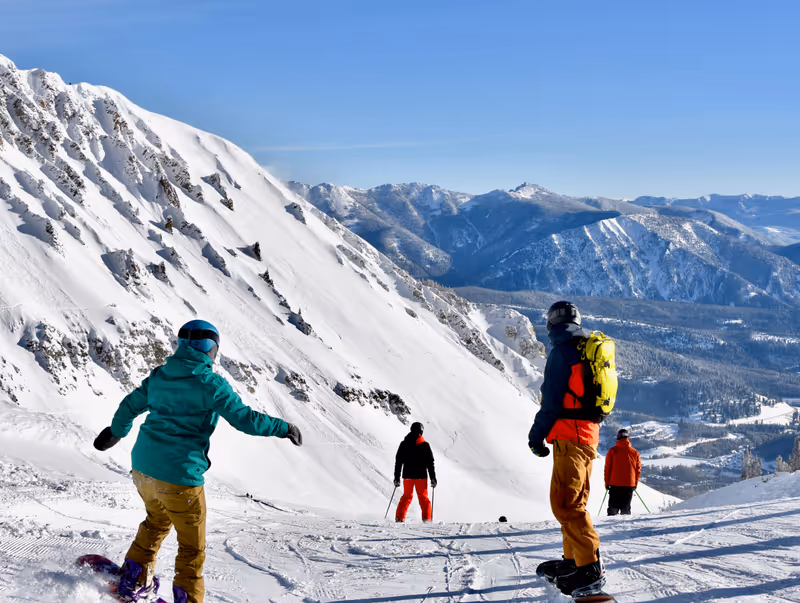 Skiers and snowboarders going over the edge at Big Sky ski resort, Montana