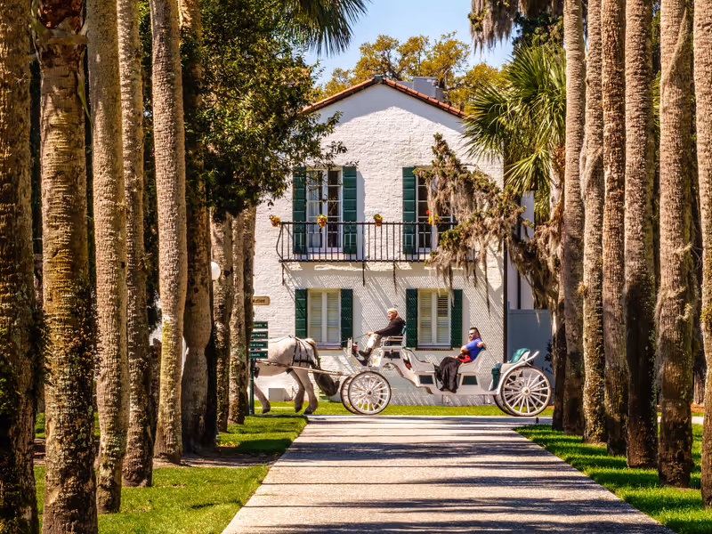 JEKYLL ISLAND, GEORGIA, USA/MARCH 20, 2019: A guide takes a couple on a leisurely horse-drawn carriage tour past Crane Cottage, built in 1918 in Mediterranean revival style, on this historic island.