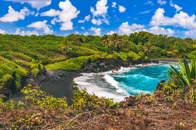 The famous black sand beach and crystal blue water at Waiʻanapanapa State Park, in Hana on the eastern side of the island of Maui, Hawaii, United States.