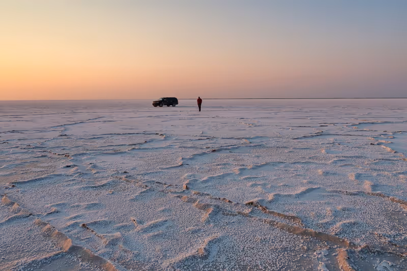 Landscape of the Bonneville Salt Flats at dawn with a man and suv in the distance