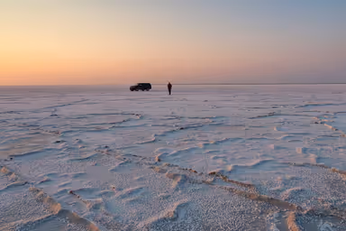 Landscape of the Bonneville Salt Flats at dawn with a man and suv in the distance