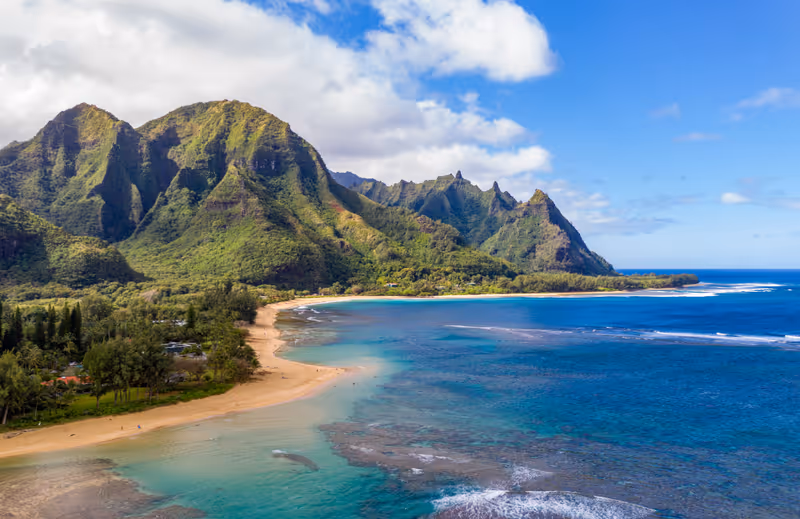 Aerial shot off the coast over Tunnels beach on Hawaiian island of Kauai with Na Pali mountains behind