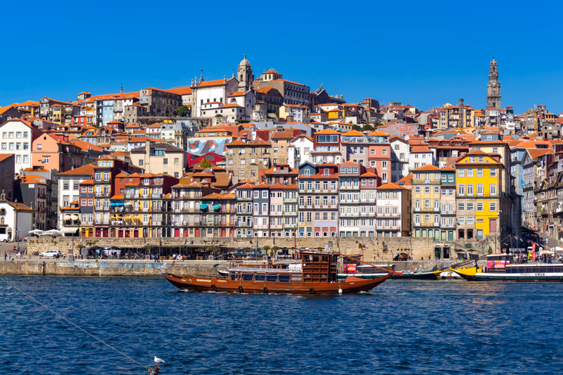PORTO, PORTUGAL - CIRCA SEPTEMBER, 2017: Boat sails on the Douro River with the Cais da Ribeira in the background, in the city of Porto, Portugal