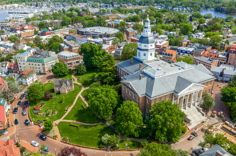 Aerial view of Maryland State House capitol building white dome and state circle with colonial houses in Annapolis on a sunny weekend afternoon