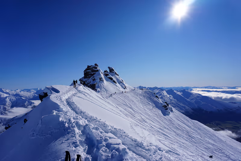View of the summit of Treble Cone on a perfect bluebird powder day. Deep hiking footprints in the snow