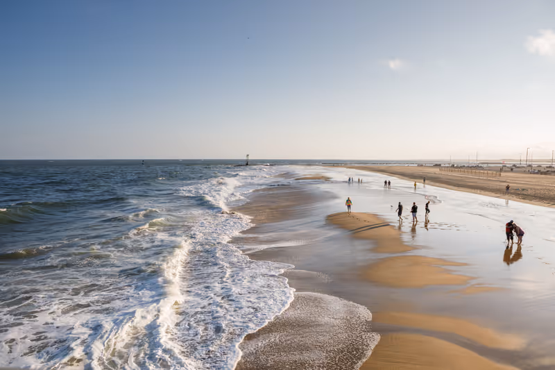 Ocean City, MD USA - October 6, 2018: Tourists walk along the southern tip of Ocean City Beach on the Atlantic Ocean in late afternoon on a sunny autumn day