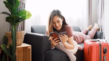 Attractive Asian woman with travel baggage have using smartphone booking flight tickets in online website and Purchase, Pay by credit card. Woman success booking travel tickets in promotion time.