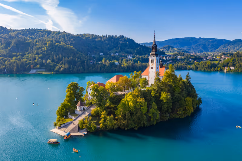 Bled, Slovenia - Aerial view of beautiful Pilgrimage Church of the Assumption of Maria on a small island at Lake Bled and lots of Pletna boats on the lake at summer time