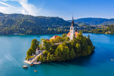 Bled, Slovenia - Aerial view of beautiful Pilgrimage Church of the Assumption of Maria on a small island at Lake Bled and lots of Pletna boats on the lake at summer time