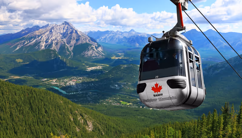 Sulphur Mountain Gondola on a blue sky with snow peaked Rocky Mountains background (Banff. Alberta. Canada)