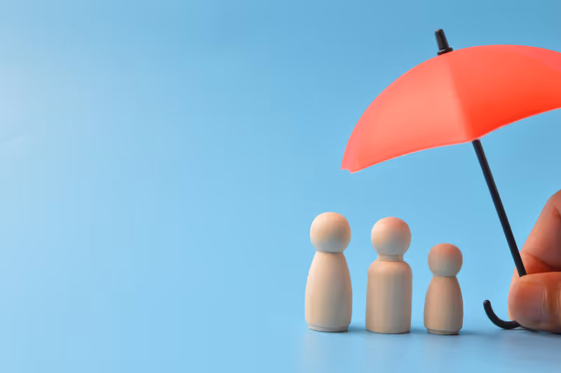 Red toy umbrella and wooden doll figures isolated on a blue background. Insurance coverage concept.