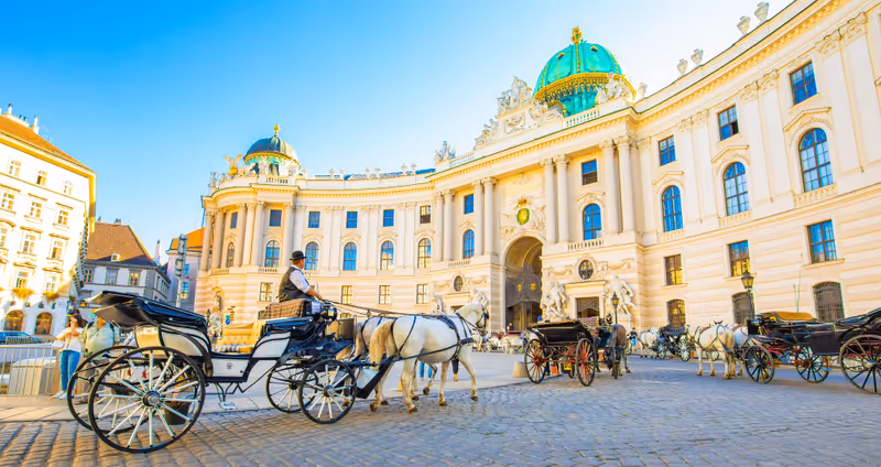 Vienna, Austria - 10 September, 2021: Hofburg palace and horse carriage on sunny Wien street. Hofburg palace is a popular tourist attraction in Vienna.