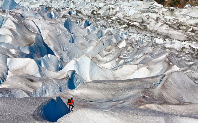 Male ice hiker in red jacket shot from behind on Mendenhall Glacier, Juneau, Alaksa