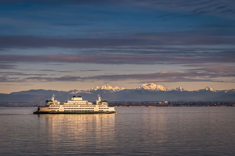 A WASHINGTON STATE FERRY IN THE PUGET SOUND WITH A NICE REFLECTION AND THE OLYMPIC MOUNTIANS IN THE BACKGROUND