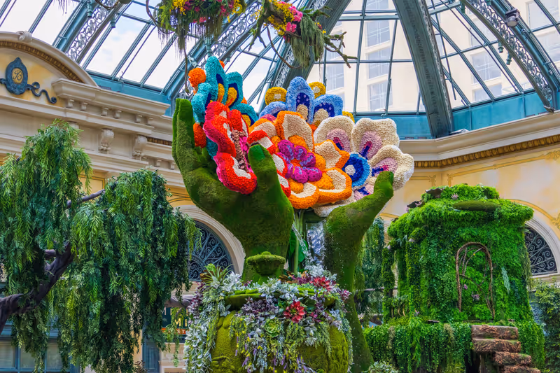 Las Vegas, Nevada USA - 6 10 2023: A flower sculpture in the shape of hands holding flowers at Bellagio Conservatory and Botanical Gardens with colorful flowers and lush green trees at the Bellagio