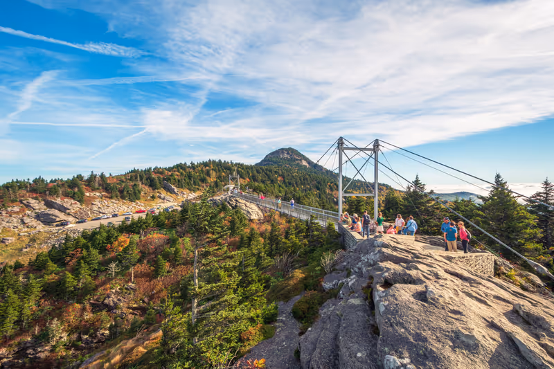 Linville , North Carolina,USA - Oct 03 2021 : People are hiking on Grandfather mountain trail with view of Mile High Swinging Bridge on background in Grandfather mountain state park.
