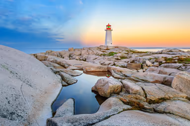The iconic lighthouse at Peggy&#39;s Cove, Nova Scotia reflecting in a pool of water in early morning light