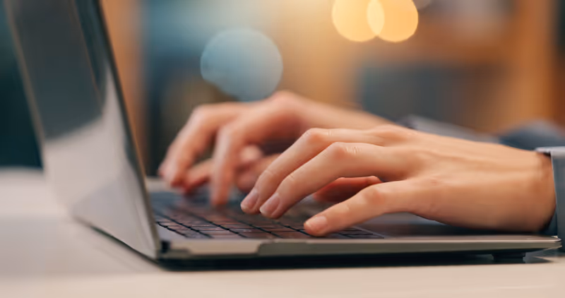 Person, hands and typing on laptop in office for email, spreadsheet and proposal or application for work. Woman, online and technology with bokeh for task or drafting, writing notes and report.