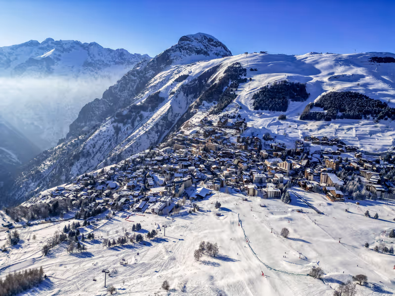 A stunning aerial winter landscape of Les Deux Alpes in France, featuring the majestic snow-capped mountains