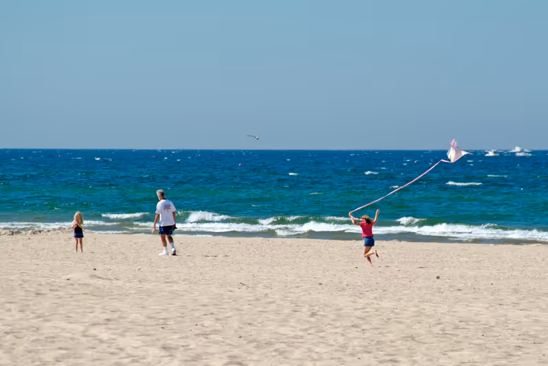 Girl flies kite on beach at Grand Haven State Park on Lake Michigan. Created 10.25.24