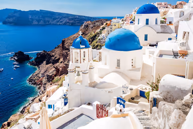 Oia town on Santorini island, Greece. Traditional and famous white houses and churches with blue domes over the Caldera, Aegean sea