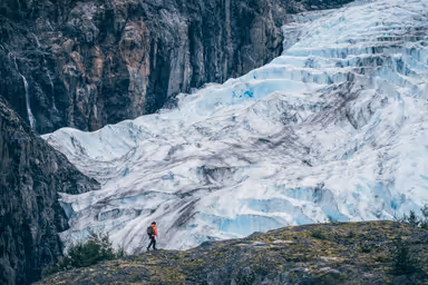 Girl walking with a backpack in front of Exit Glacier, Seward, Alaska