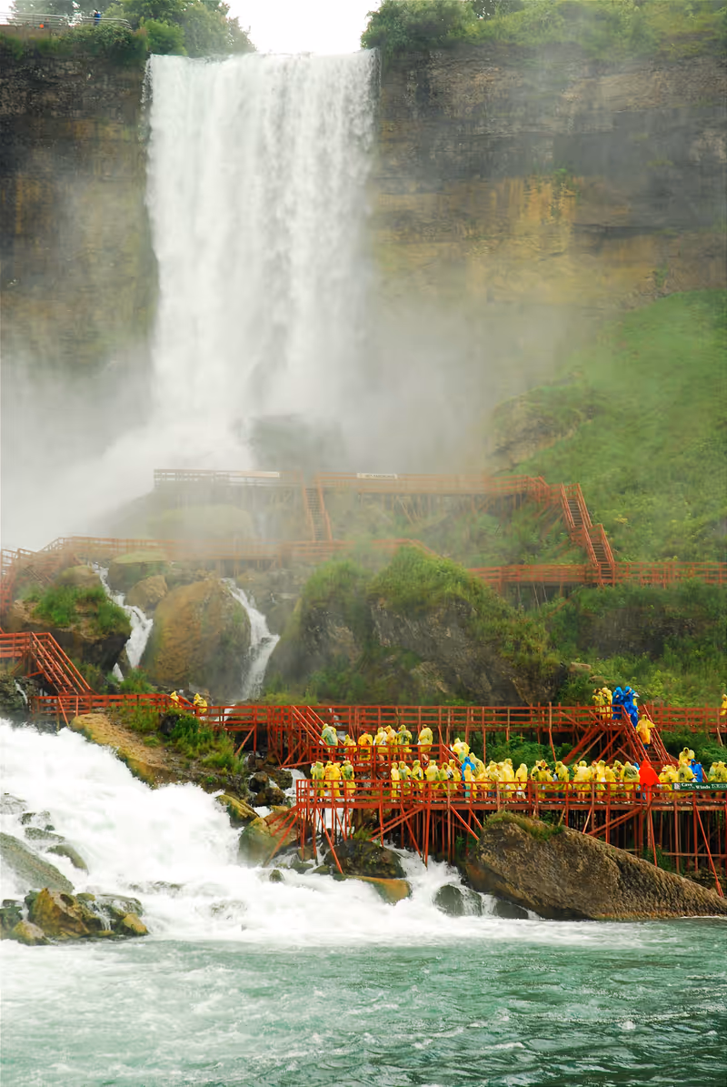 Niagara Falls, NY, USA August 7 Yellow poncho cladded visitors stroll along the wooden walkway at the base of the American Falls in Niagara Falls, New York